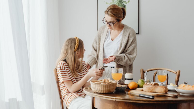 Two teenagers talking with an adult at a kitchen table