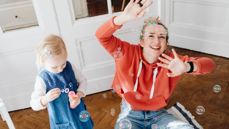 Mother and young child sitting together on a floor, engaged in play
