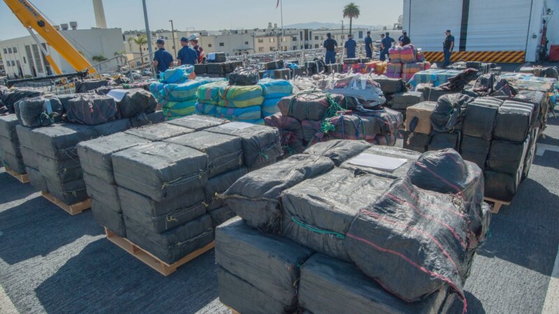 U.S. Coast Guard personnel with bales of seized cocaine stacked on a vessel deck - U.S. Coast Guard photo via DVIDS (dvidshub.net)