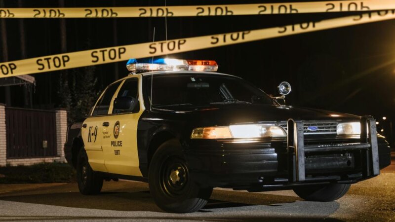 Police car parked beside a crime scene with emergency lights