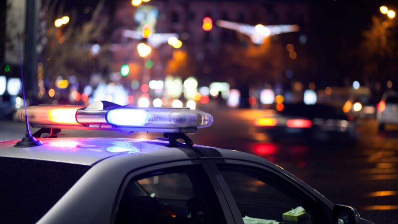 Police car with flashing lights at night during manhunt
