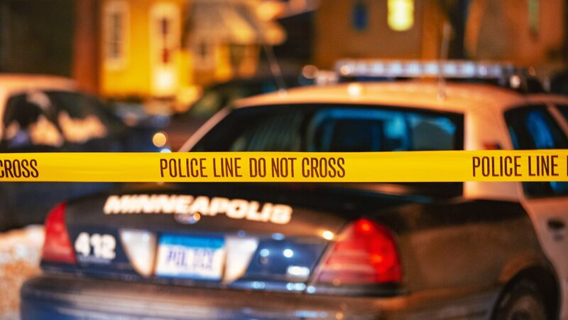 Police crime scene tape in front of a squad car